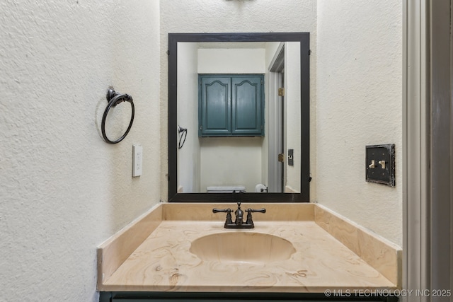 bathroom with vanity and a textured wall