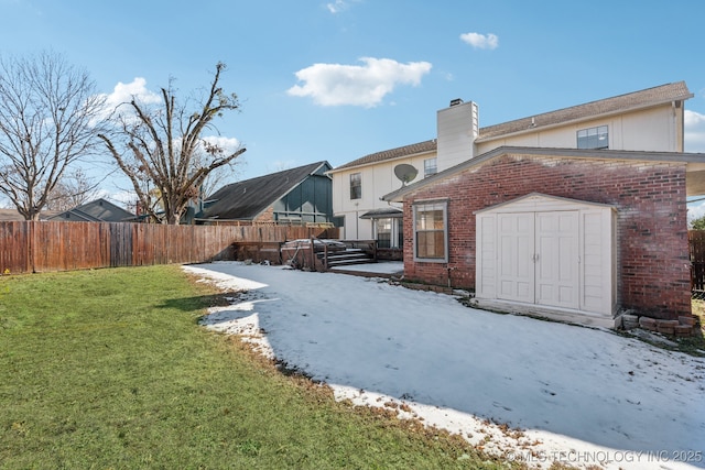 rear view of house featuring an outbuilding, a shed, fence, a yard, and brick siding