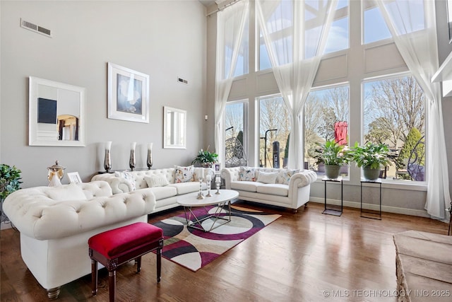 living room featuring a towering ceiling, a wealth of natural light, and hardwood / wood-style flooring