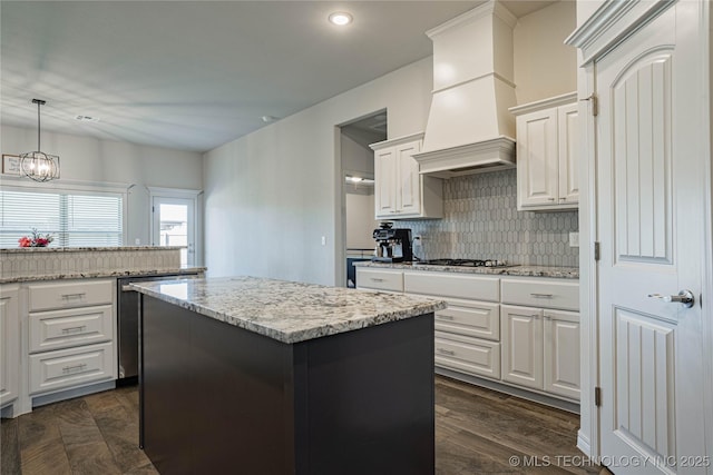 kitchen with tasteful backsplash, dark hardwood / wood-style floors, pendant lighting, a center island, and white cabinetry