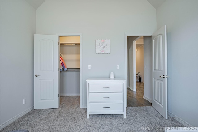 unfurnished bedroom featuring a spacious closet, a closet, lofted ceiling, and light carpet