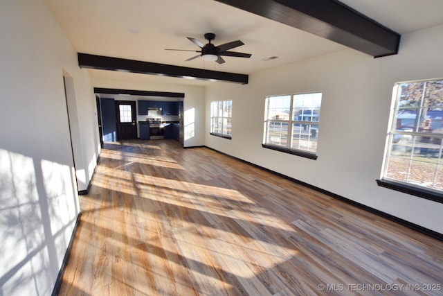 unfurnished living room with hardwood / wood-style flooring, plenty of natural light, and beam ceiling