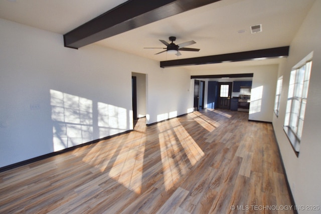 unfurnished living room with beam ceiling, wood-type flooring, and ceiling fan