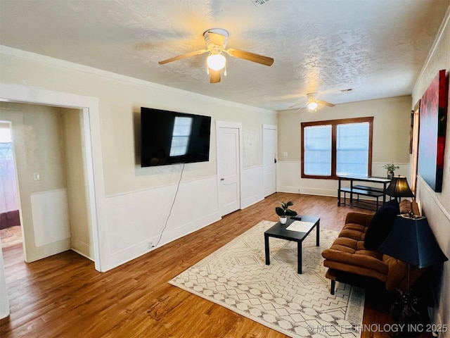 living room featuring hardwood / wood-style flooring, a textured ceiling, and ceiling fan