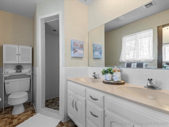 bathroom featuring tile walls, walk in shower, vanity, and toilet