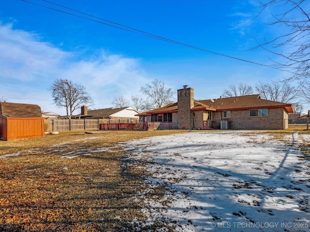 snow covered back of property with central air condition unit and a storage shed