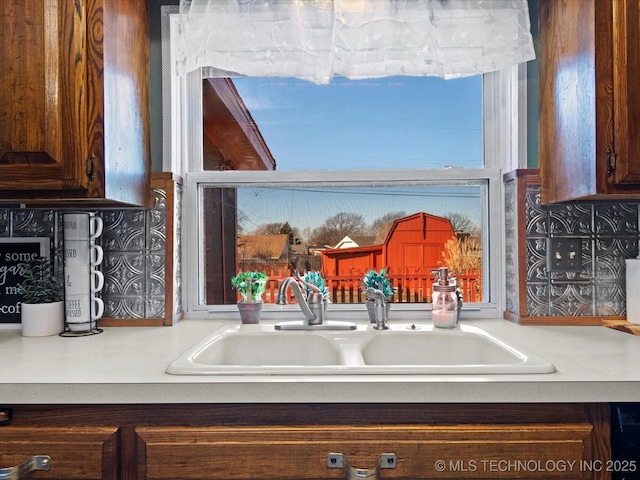 details with tasteful backsplash, dark brown cabinetry, and sink