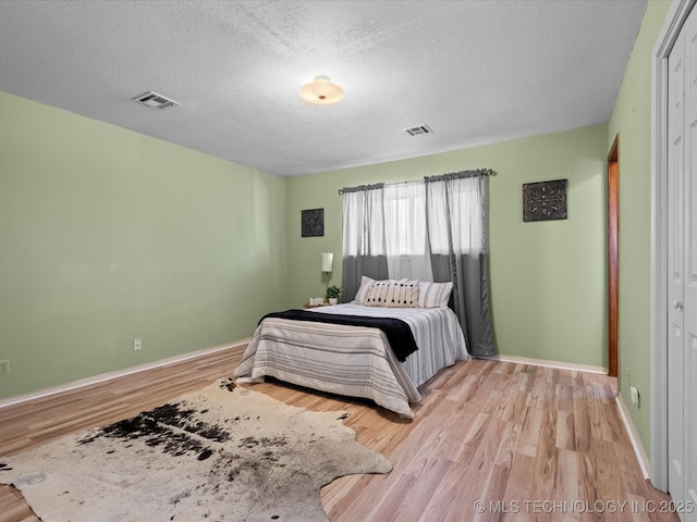 bedroom featuring a textured ceiling and light hardwood / wood-style floors