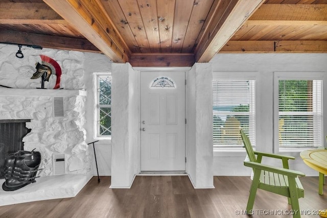 entryway with dark hardwood / wood-style flooring, beamed ceiling, a stone fireplace, and wooden ceiling