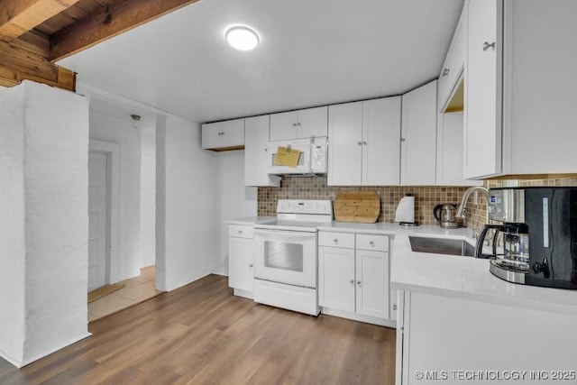 kitchen with white appliances, hardwood / wood-style floors, white cabinetry, tasteful backsplash, and sink