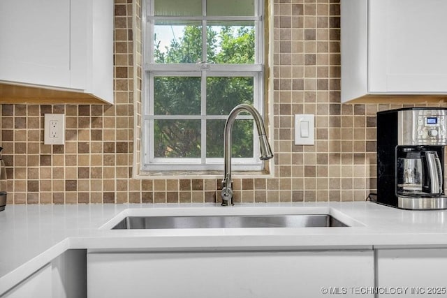 kitchen with white cabinets, backsplash, and sink