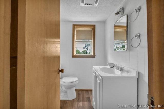 bathroom with toilet, vanity, wood-type flooring, and a textured ceiling