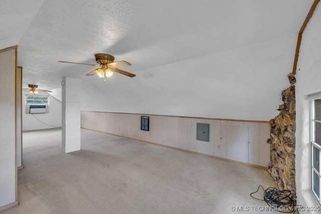 additional living space with a textured ceiling, vaulted ceiling, and wood walls