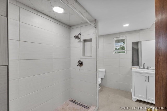 bathroom with a shower, tile walls, toilet, and vanity