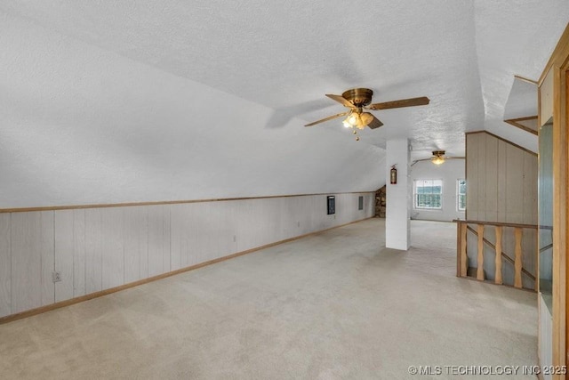 additional living space with ceiling fan, a textured ceiling, light carpet, and lofted ceiling