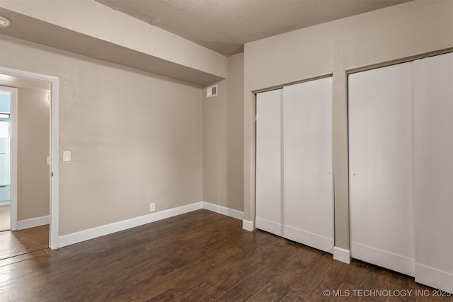 unfurnished bedroom featuring multiple closets and dark hardwood / wood-style flooring