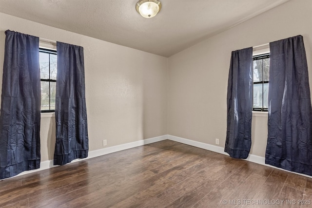 spare room with a textured ceiling and dark hardwood / wood-style flooring