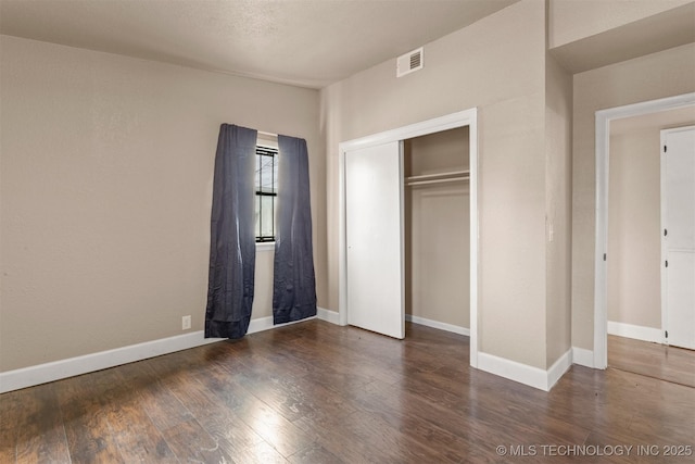 unfurnished bedroom featuring a closet and dark hardwood / wood-style floors