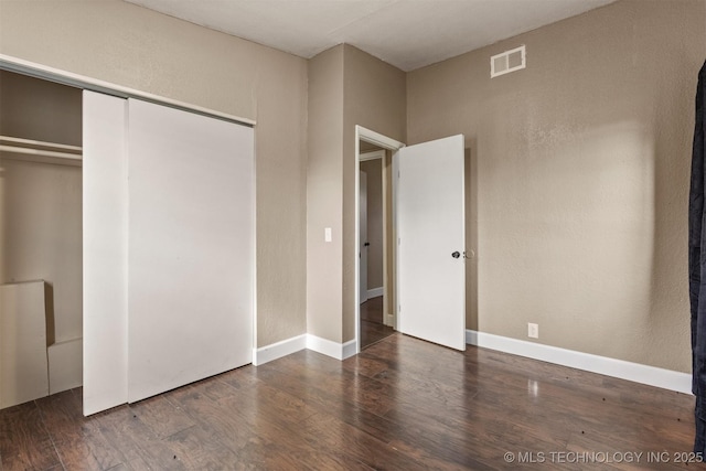 unfurnished bedroom with a closet and dark hardwood / wood-style flooring