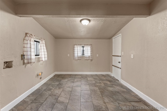 empty room featuring a textured ceiling and lofted ceiling