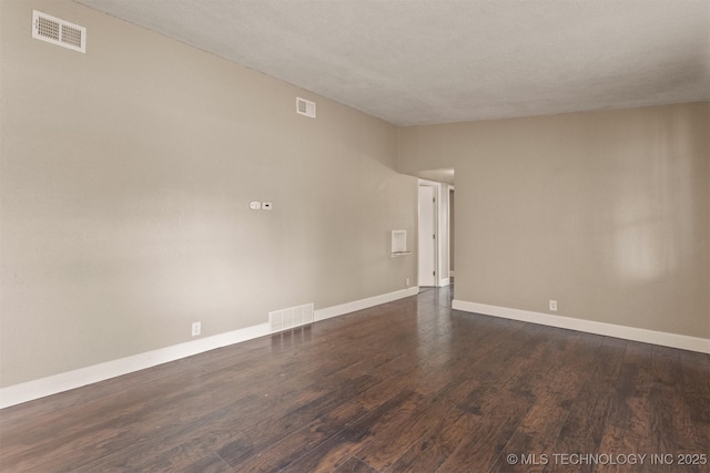 unfurnished room with dark wood-type flooring and a textured ceiling