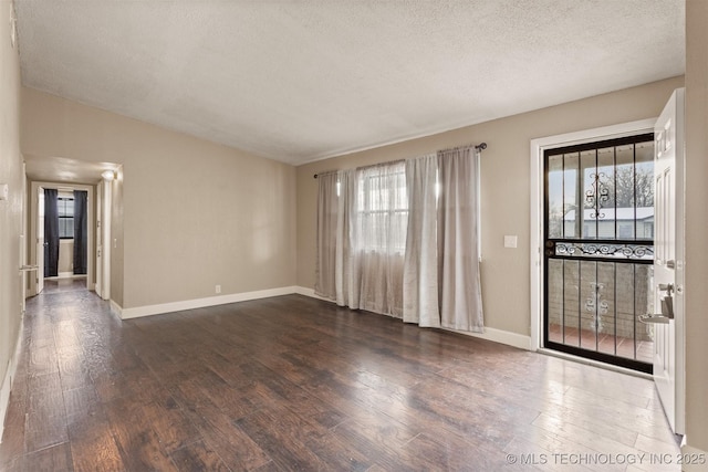 empty room with a textured ceiling and dark hardwood / wood-style flooring