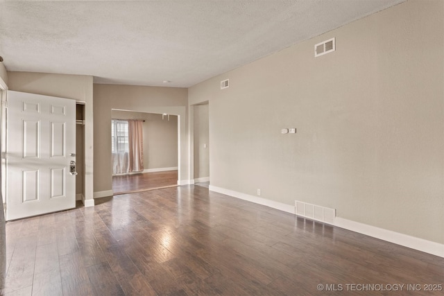 spare room featuring dark wood-type flooring and a textured ceiling