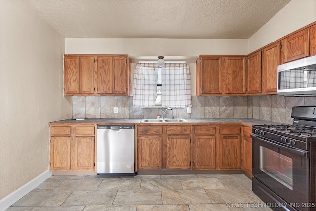 kitchen with backsplash, appliances with stainless steel finishes, sink, and a textured ceiling