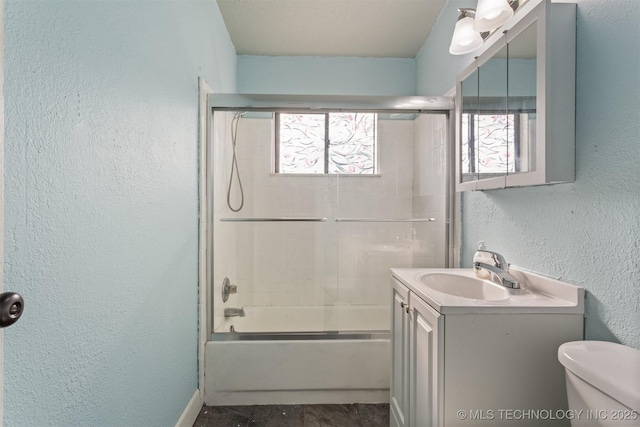 full bathroom featuring a wealth of natural light, toilet, vanity, and shower / bath combination with glass door