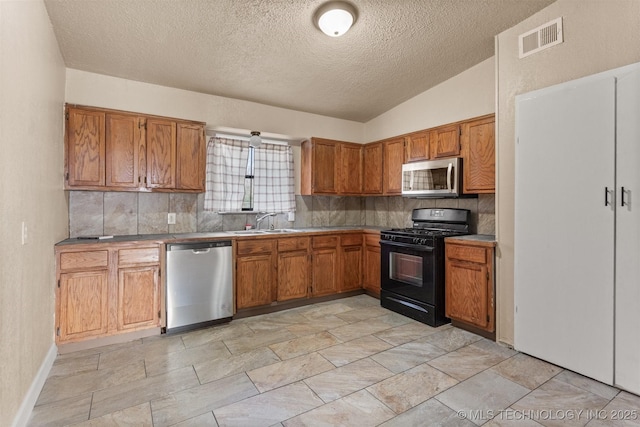 kitchen featuring sink, backsplash, stainless steel appliances, and vaulted ceiling