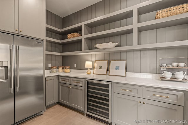 kitchen with light wood-type flooring, beverage cooler, gray cabinets, and built in fridge