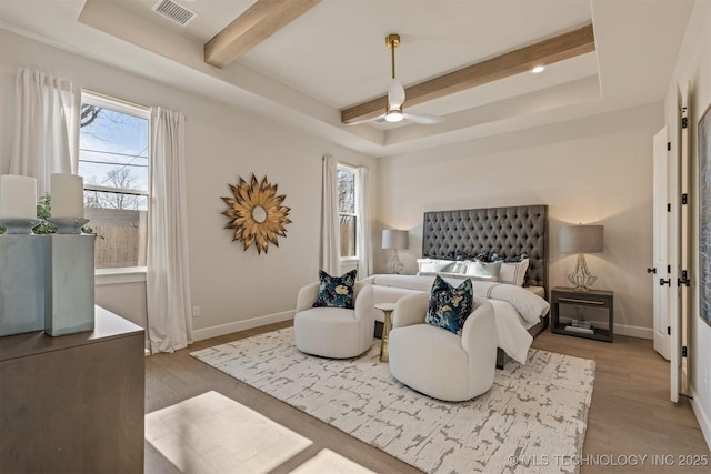 bedroom with a raised ceiling, multiple windows, and hardwood / wood-style floors