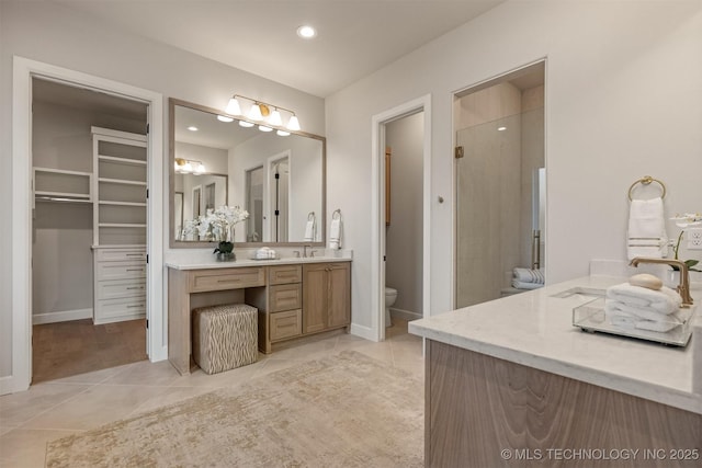 bathroom with toilet, vanity, tile patterned floors, and walk in shower