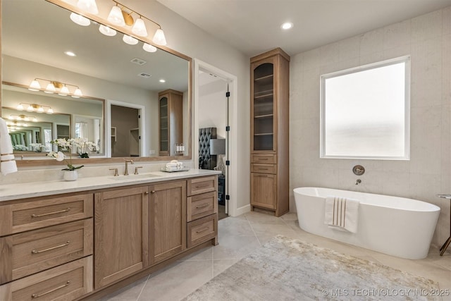 bathroom with a tub, vanity, and tile patterned flooring