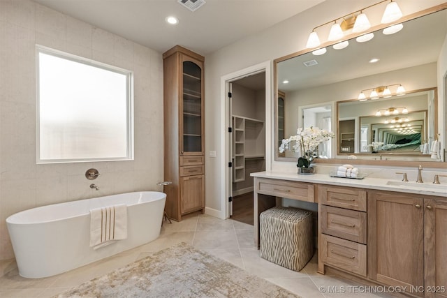 bathroom with tile patterned flooring, a bath, tile walls, and vanity