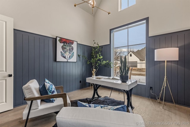 home office with light wood-type flooring, plenty of natural light, and an inviting chandelier