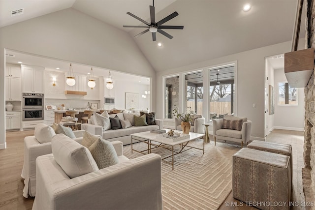 living room featuring light wood-type flooring, ceiling fan, and high vaulted ceiling