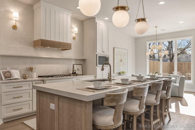 kitchen featuring appliances with stainless steel finishes, sink, white cabinetry, and pendant lighting