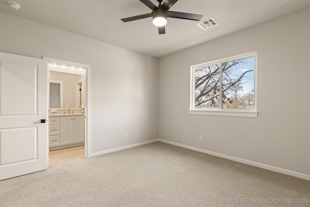 unfurnished bedroom with ceiling fan, ensuite bathroom, light colored carpet, and sink