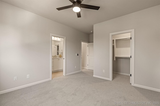 unfurnished bedroom featuring ceiling fan, light colored carpet, ensuite bath, a walk in closet, and a closet