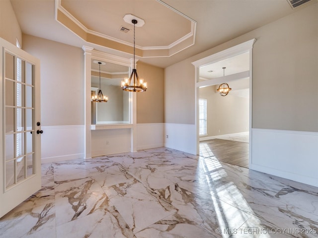 unfurnished dining area featuring a tray ceiling, crown molding, and a notable chandelier