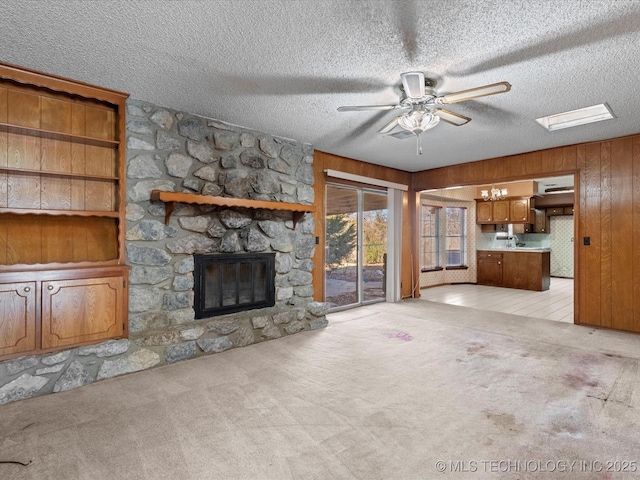 unfurnished living room featuring a fireplace, light colored carpet, and wooden walls