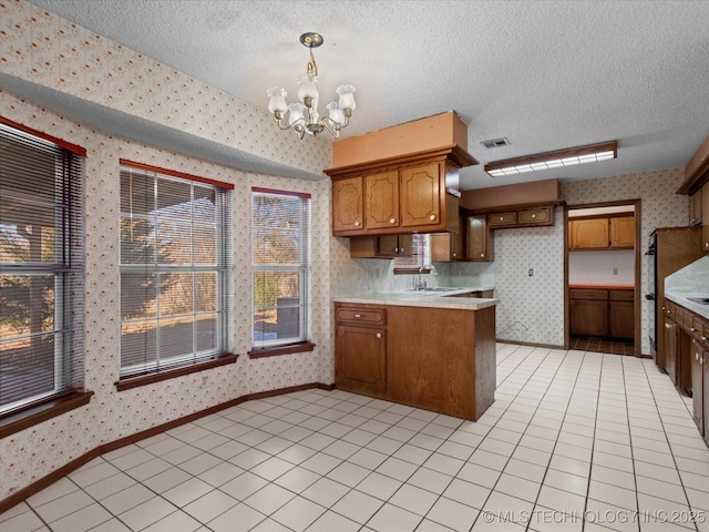 kitchen with hanging light fixtures, sink, a chandelier, and a textured ceiling