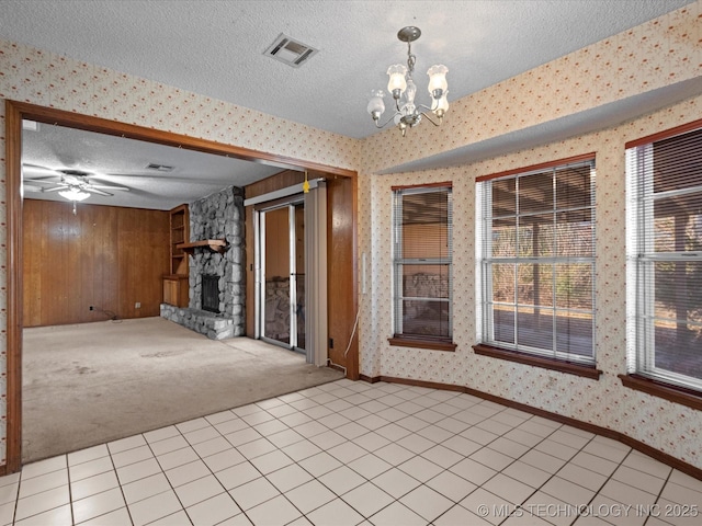 interior space featuring light carpet, wooden walls, a fireplace, a textured ceiling, and ceiling fan with notable chandelier