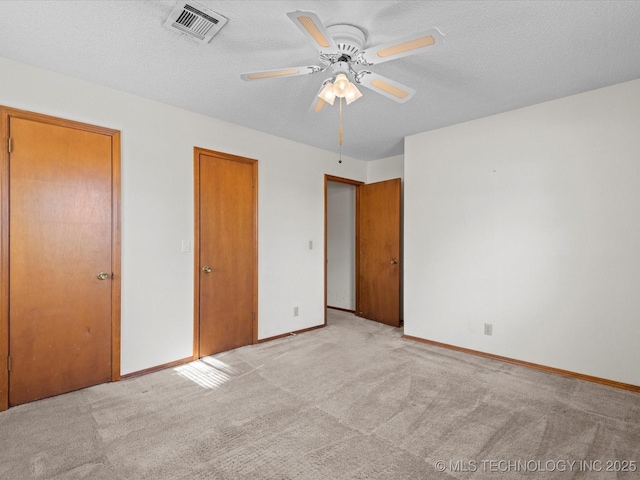 unfurnished bedroom featuring ceiling fan, a textured ceiling, and light carpet