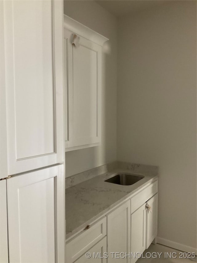 kitchen featuring light stone countertops, white cabinetry, and tile patterned flooring