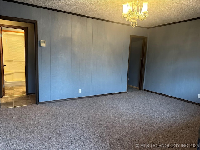 carpeted spare room with ornamental molding, a chandelier, and a textured ceiling