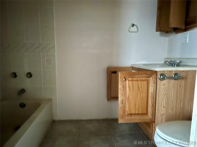 bathroom with a tub, sink, tile patterned floors, and toilet