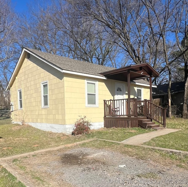 view of front of property featuring fence, a front yard, and a shingled roof