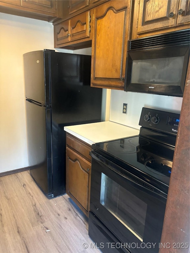 kitchen featuring light wood-type flooring and black appliances